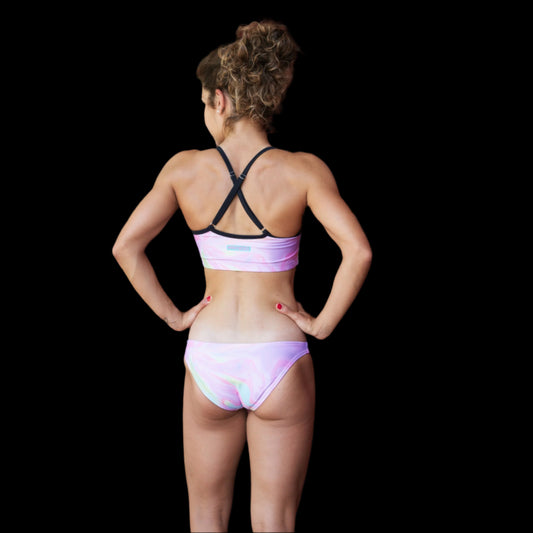 Woman in a pink bikini standing on a wooden deck with a red wooden wall in the background