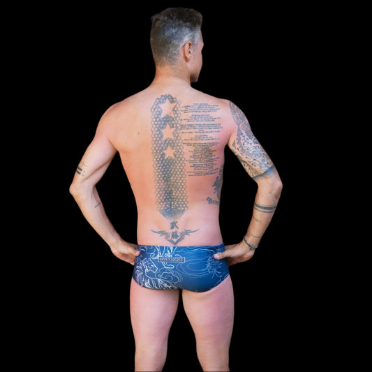 Fit man wearing Blue Flower Tiger pattern one piece swimwear with a brand logo hands on hips