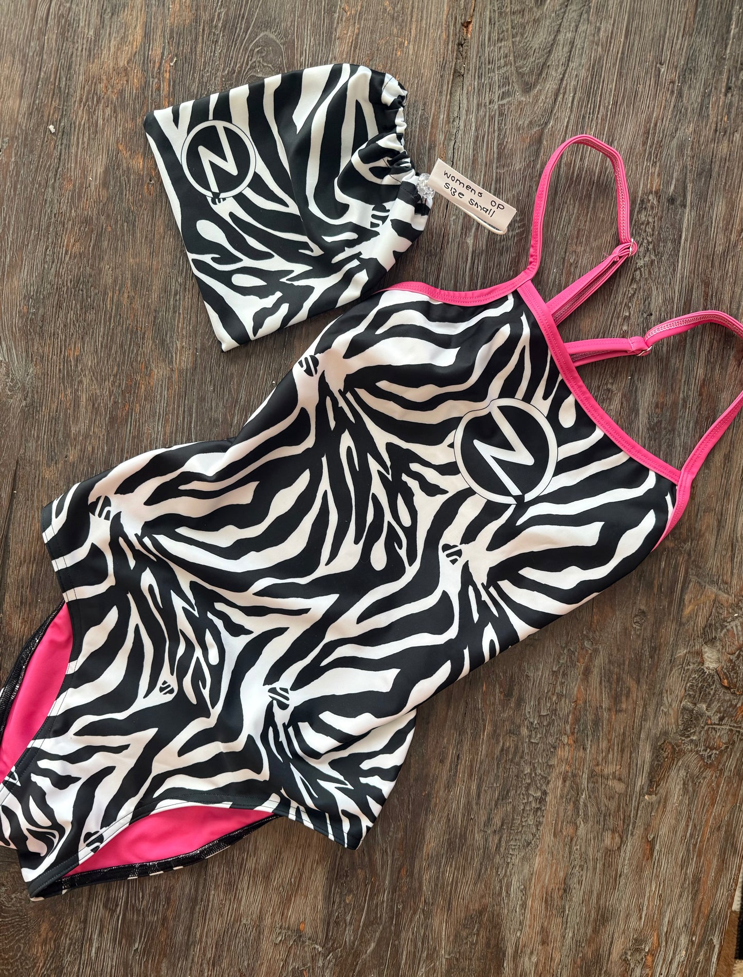 Zebra print swimsuit with pink straps on a wooden surface
