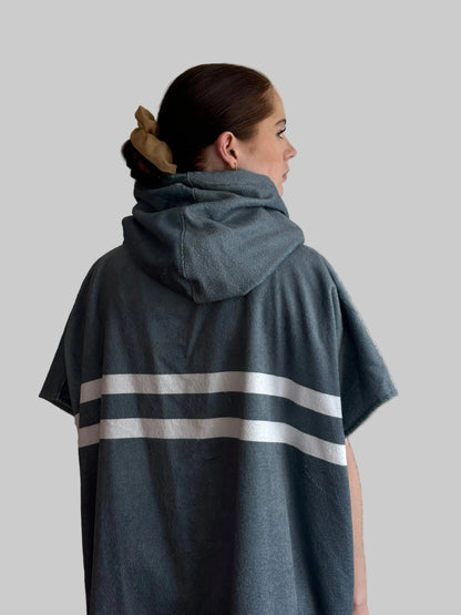 Person wearing a gray hoodie with white stripes on a plain background