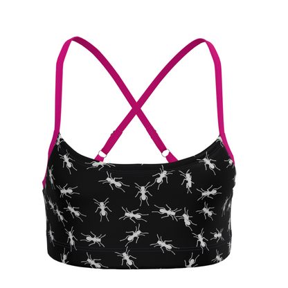 Black sports bra with white ant pattern and pink adjustable straps on a white background
