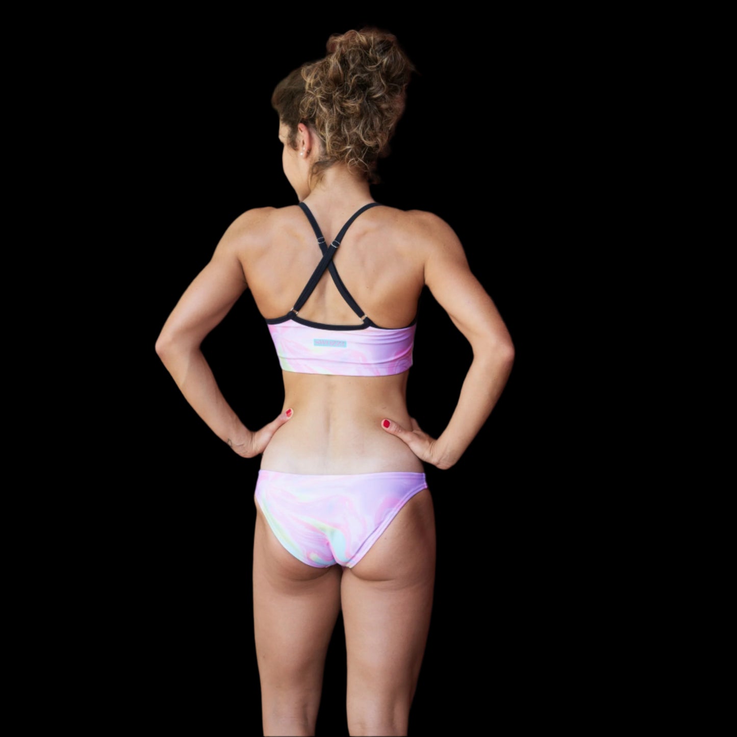 Woman in a pink swirl bikini standing on a wooden deck with a red wooden wall in the background