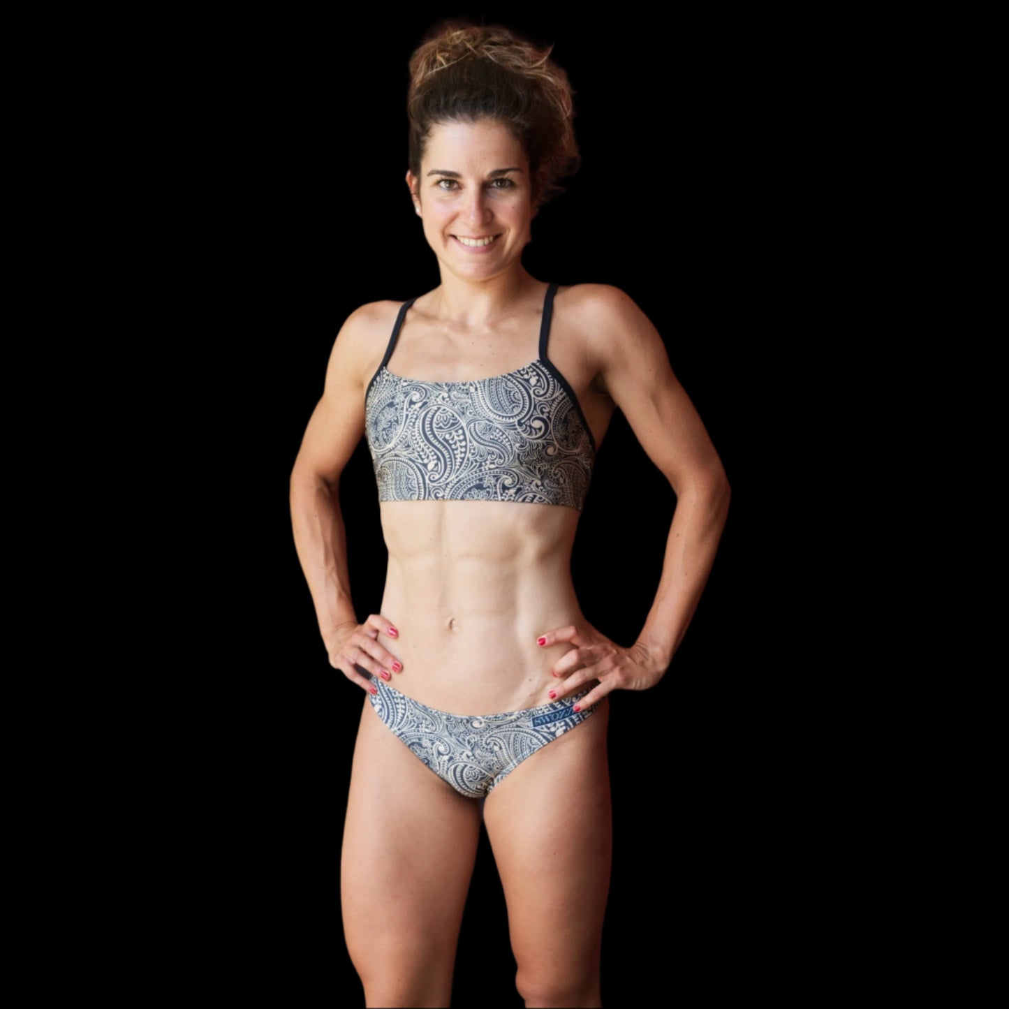 Woman wearing a patterned Paisley bikini standing against a red wooden wall.