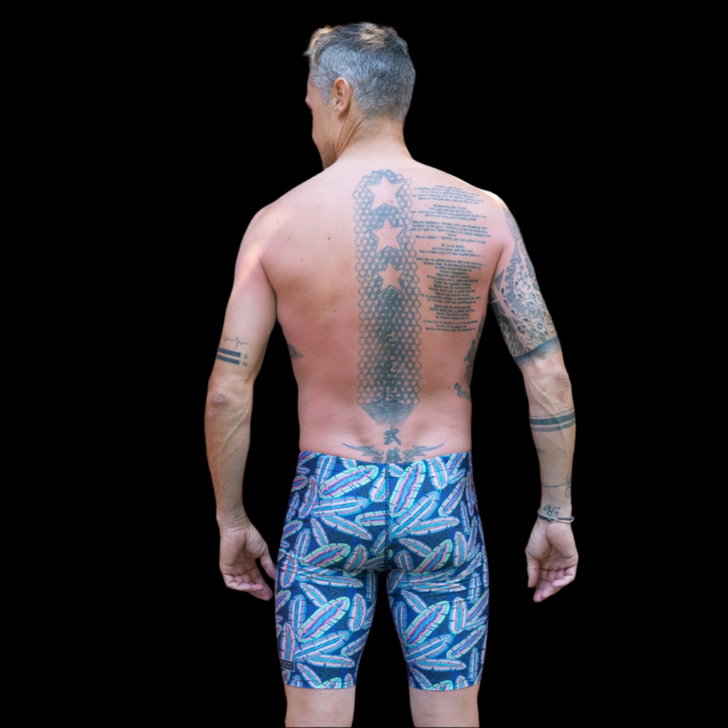 Fit Man wearing colourful feather pattern Jammers standing with hands on hips
