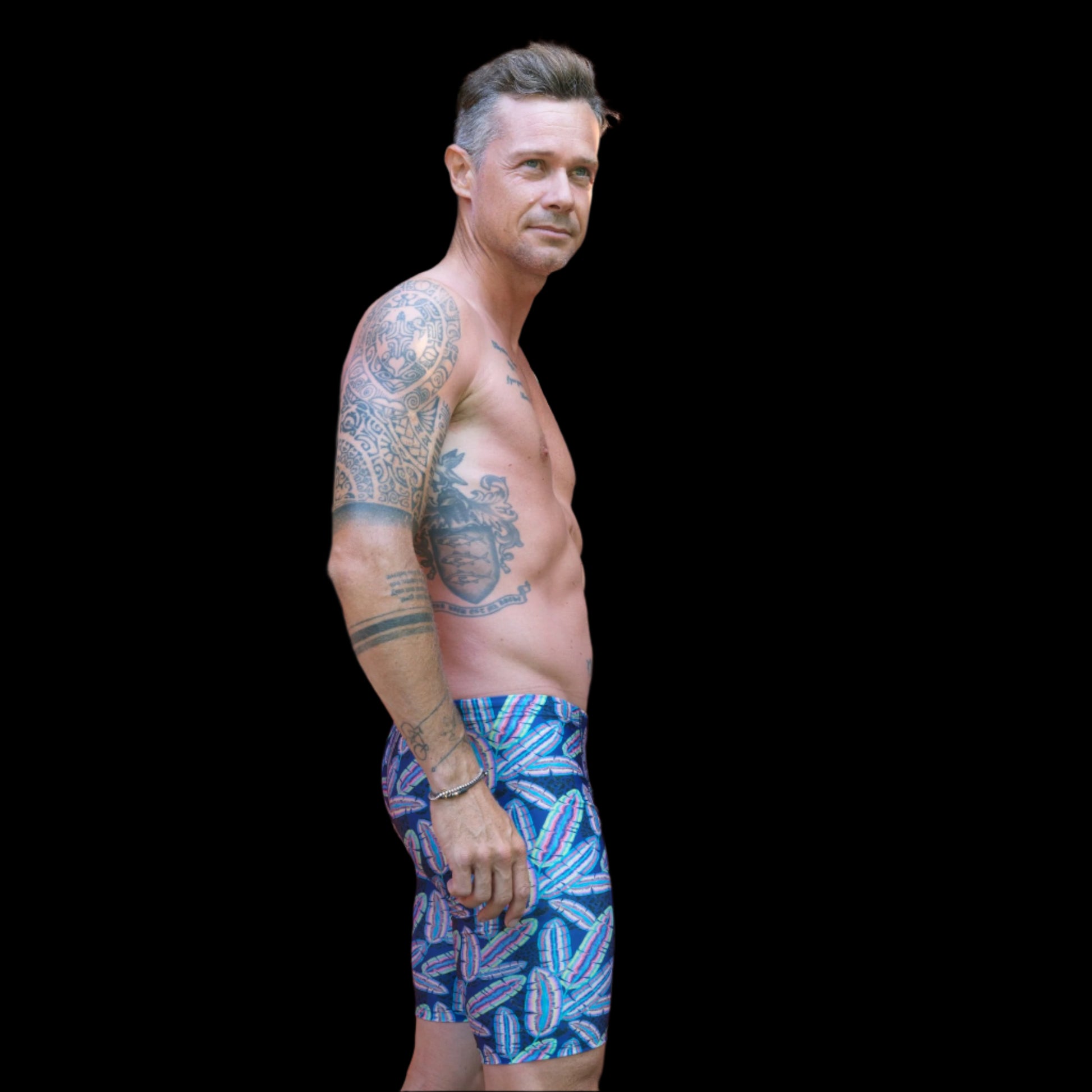 Fit Man wearing colourful feather pattern Jammers standing with hands on hips
