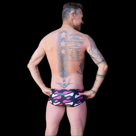 Fit man wearing Heart pattern one piece swimwear with a brand logo   hands on hips
