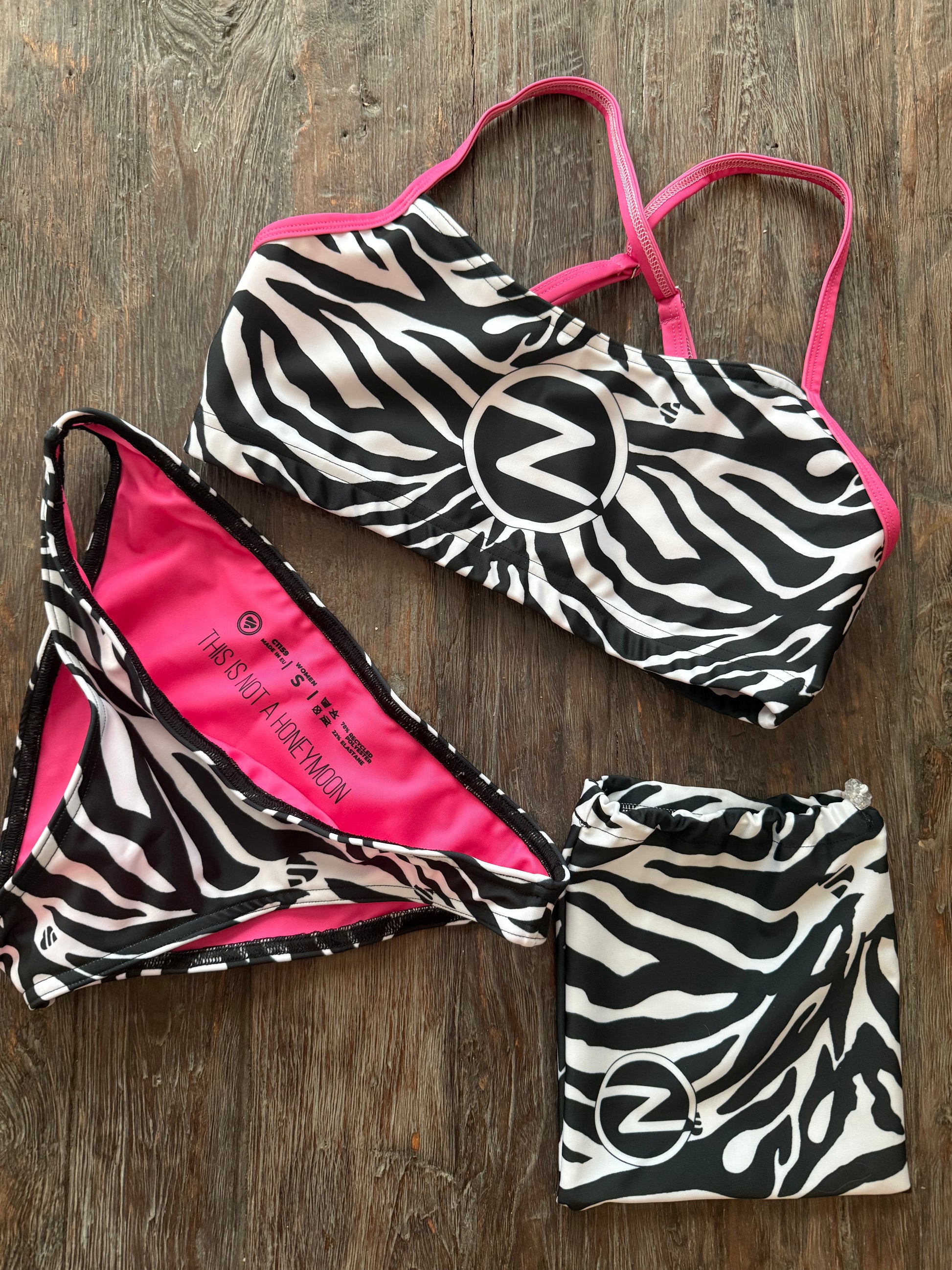 Zebra print bikini set with pink accents on a wooden surface with matching bag